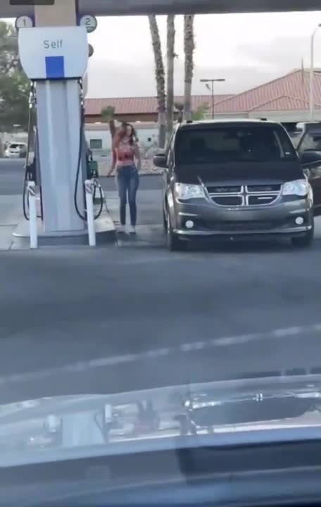 Une fille a beaucoup de mal à se garer dans une station essence