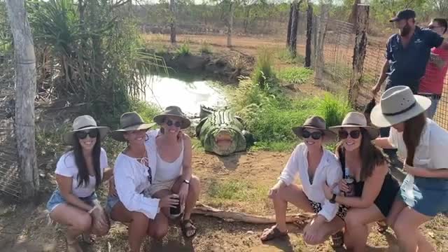 Un groupe de filles pose devant un crocodile
