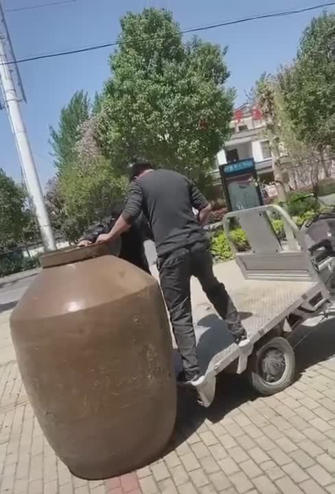 Deux Régis chargent un pot sur un petit véhicule